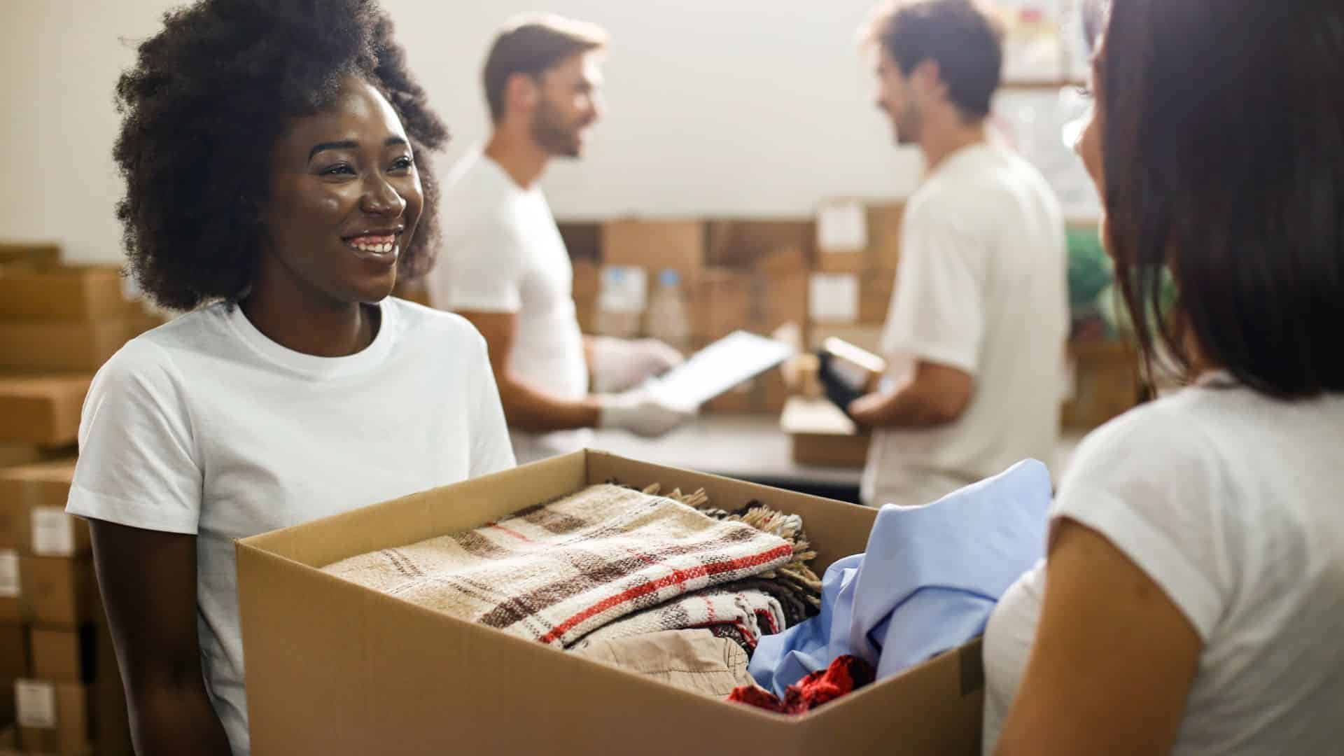 Woman being handed large box of clothing
