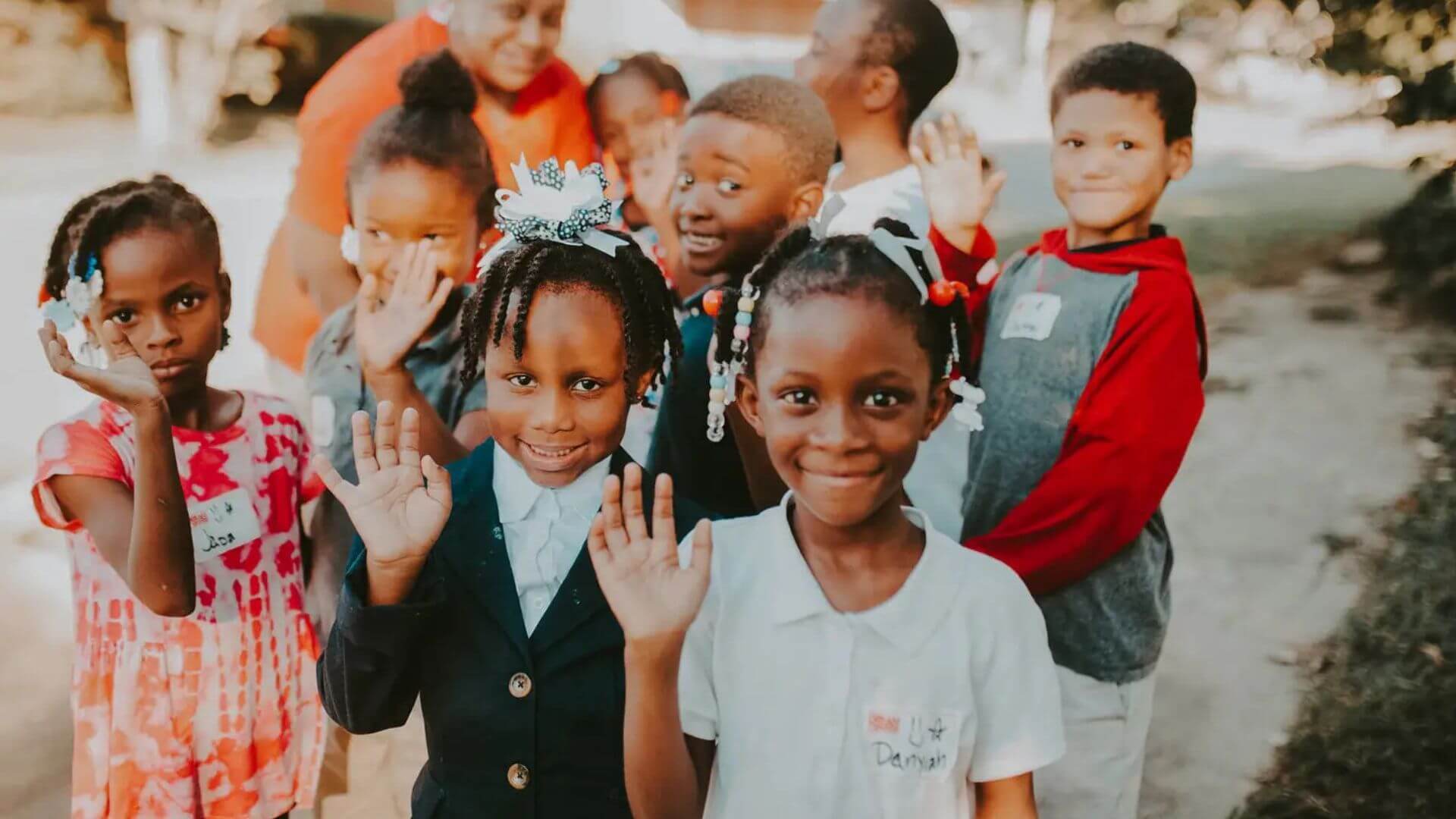 Small children smiling and waving at camera